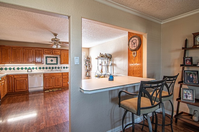 kitchen with dishwasher, dark hardwood / wood-style floors, a textured ceiling, tasteful backsplash, and a breakfast bar area