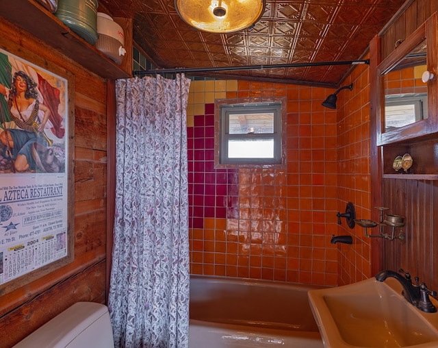 full bathroom with a wealth of natural light, wooden walls, and sink