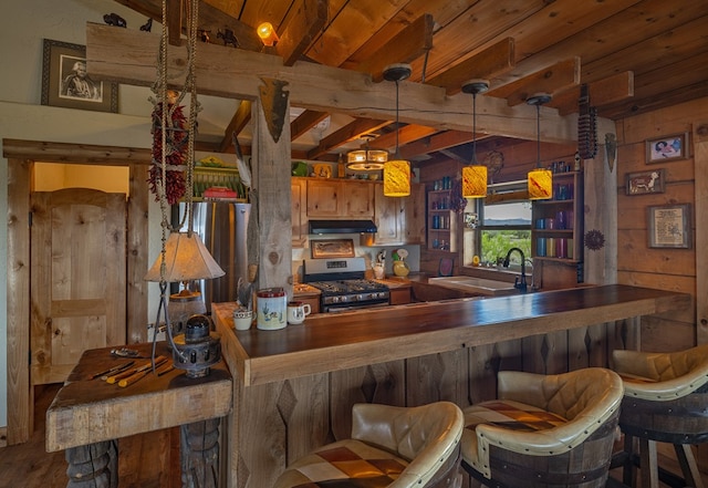 kitchen featuring beam ceiling, gas range, sink, hanging light fixtures, and hardwood / wood-style flooring