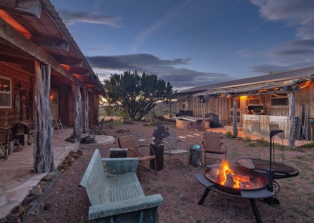 yard at dusk with area for grilling, an outdoor fire pit, and a patio