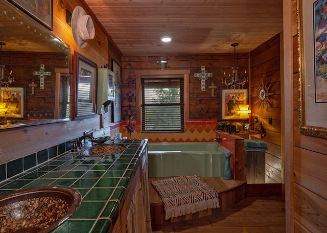 interior space with wood walls, wooden ceiling, an inviting chandelier, sink, and tile counters