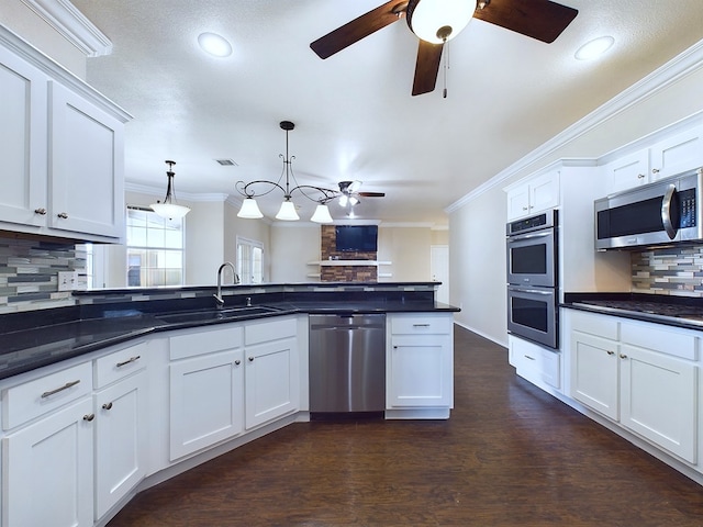 kitchen with appliances with stainless steel finishes, a sink, white cabinetry, and pendant lighting