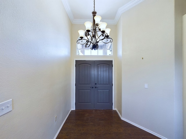 doorway featuring a chandelier, ornamental molding, dark wood-type flooring, and baseboards