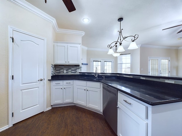 kitchen featuring a sink, white cabinets, stainless steel dishwasher, dark countertops, and pendant lighting