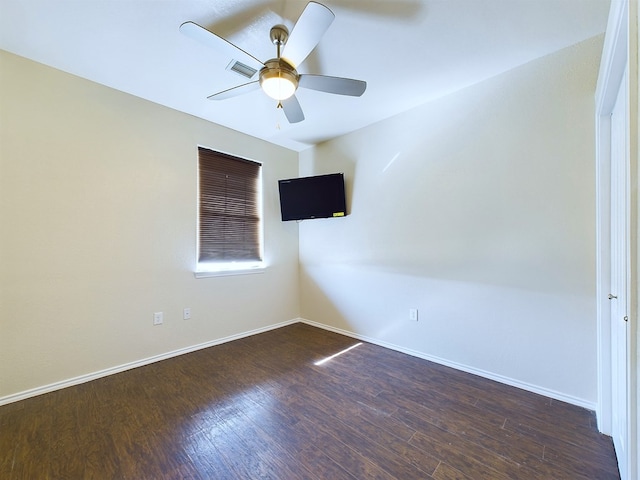 spare room featuring a ceiling fan, dark wood finished floors, visible vents, and baseboards