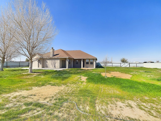 back of property with a yard, a chimney, fence, and stucco siding