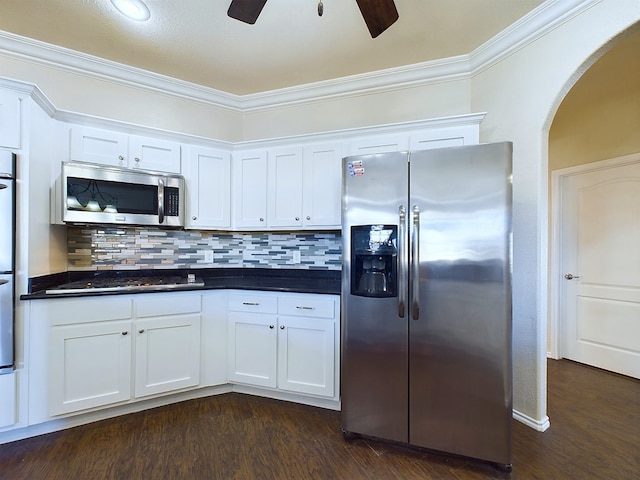 kitchen featuring stainless steel appliances, dark countertops, dark wood-style flooring, and white cabinetry