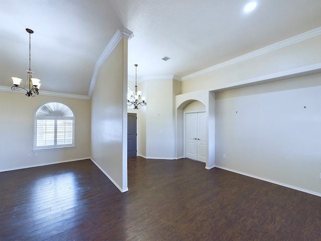 empty room with a chandelier, arched walkways, and dark wood-style floors