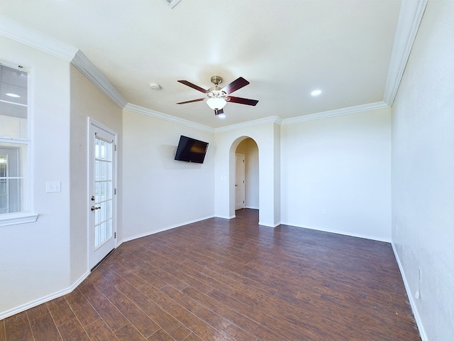 empty room with dark wood-style floors, arched walkways, ornamental molding, and a ceiling fan