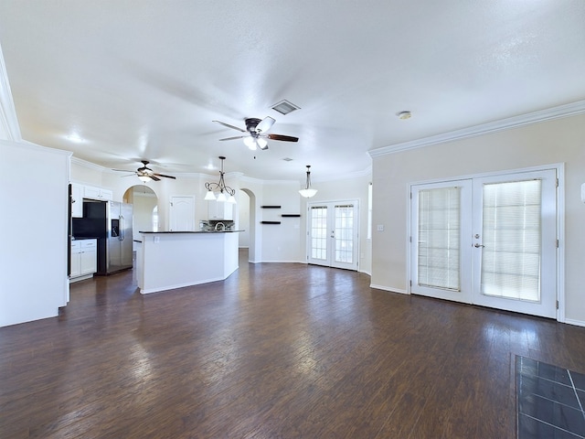 unfurnished living room with visible vents, arched walkways, a ceiling fan, dark wood-type flooring, and french doors