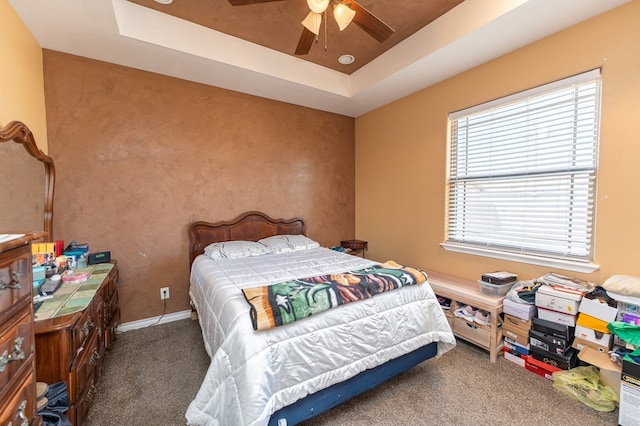 carpeted bedroom featuring ceiling fan and a tray ceiling