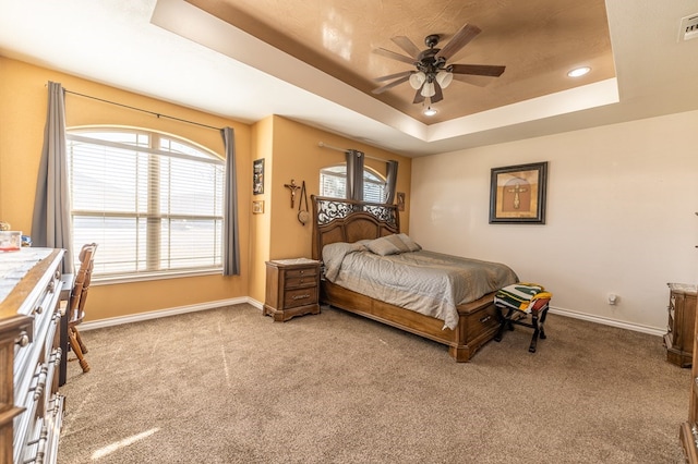 carpeted bedroom with a tray ceiling and ceiling fan