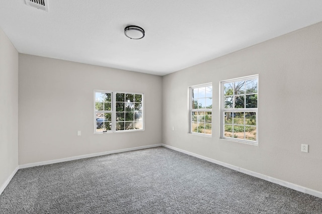 empty room featuring visible vents, plenty of natural light, and carpet flooring