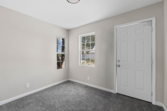 empty room featuring baseboards and dark colored carpet