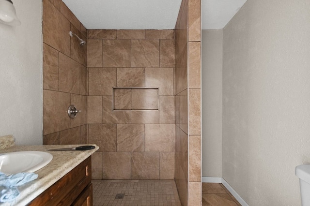 full bathroom featuring vanity, baseboards, and a tile shower