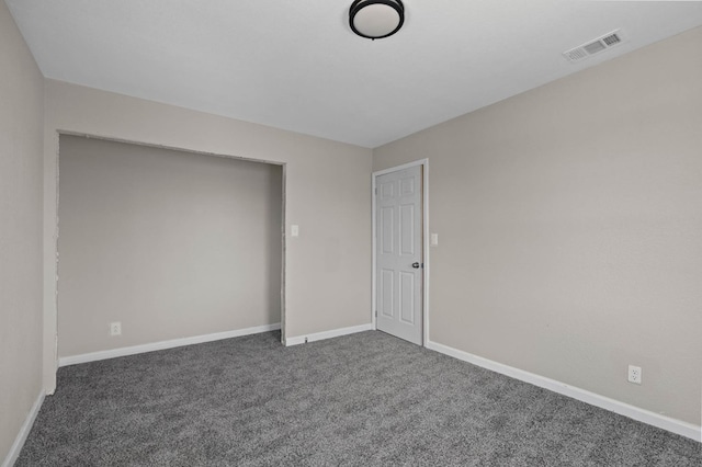 unfurnished room featuring visible vents, dark carpet, and baseboards