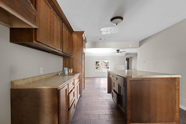 kitchen with a kitchen island, light countertops, a ceiling fan, and wood tiled floor