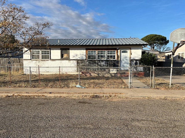 view of front of property with a fenced front yard, a gate, metal roof, and concrete block siding