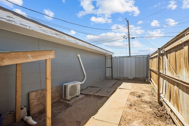 view of side of property with a wall unit AC and a fenced backyard