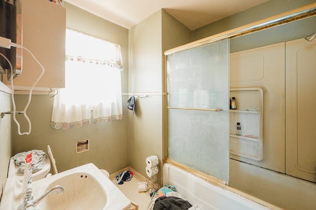 bathroom featuring bath / shower combo with glass door and sink