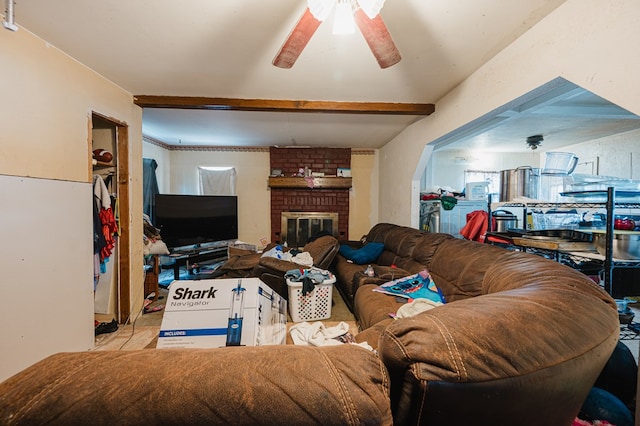 living room with ceiling fan, beam ceiling, and a brick fireplace