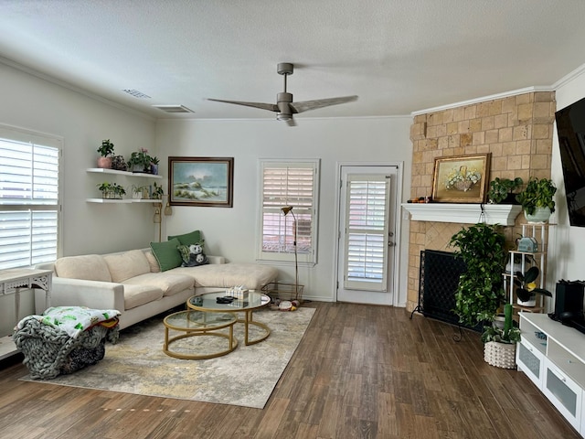 living room featuring a textured ceiling, plenty of natural light, dark wood-type flooring, and a tiled fireplace