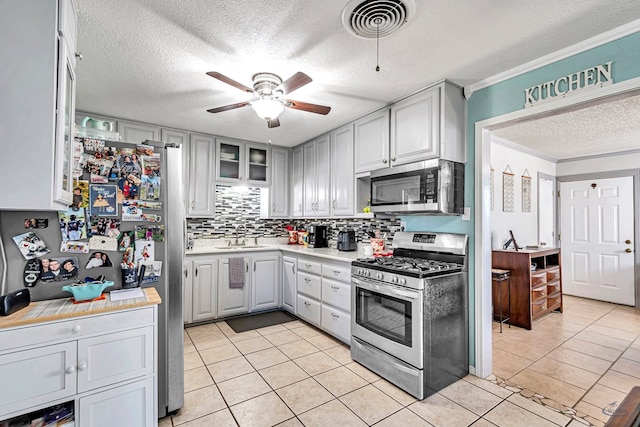 kitchen featuring sink, ornamental molding, ceiling fan, stainless steel appliances, and a textured ceiling