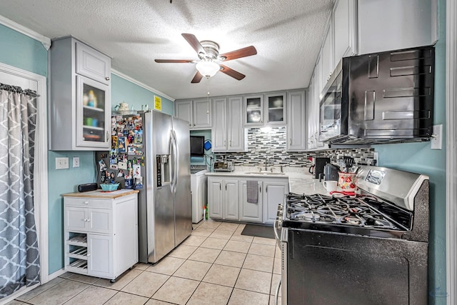 kitchen featuring appliances with stainless steel finishes, washer / dryer, sink, backsplash, and light tile patterned floors