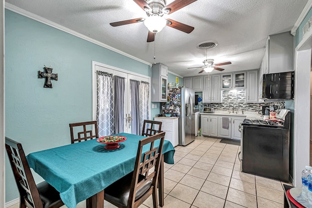 kitchen with backsplash, crown molding, gas stove, and light tile patterned flooring