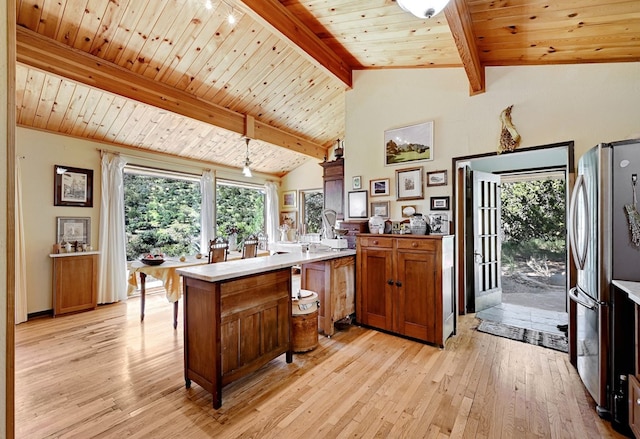 kitchen with vaulted ceiling with beams, kitchen peninsula, stainless steel fridge, light hardwood / wood-style floors, and wood ceiling