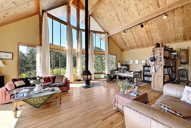 living room with beam ceiling, a wood stove, a wealth of natural light, and light hardwood / wood-style floors