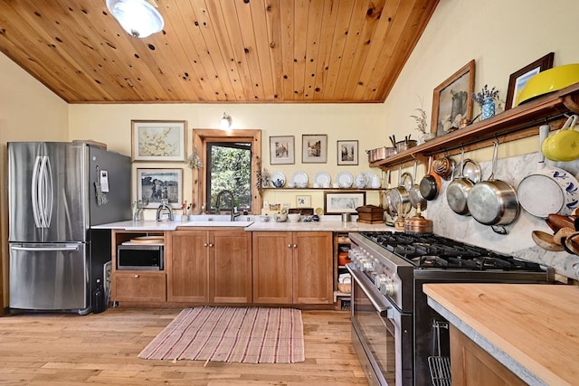 kitchen with appliances with stainless steel finishes, vaulted ceiling, sink, wooden ceiling, and light hardwood / wood-style floors