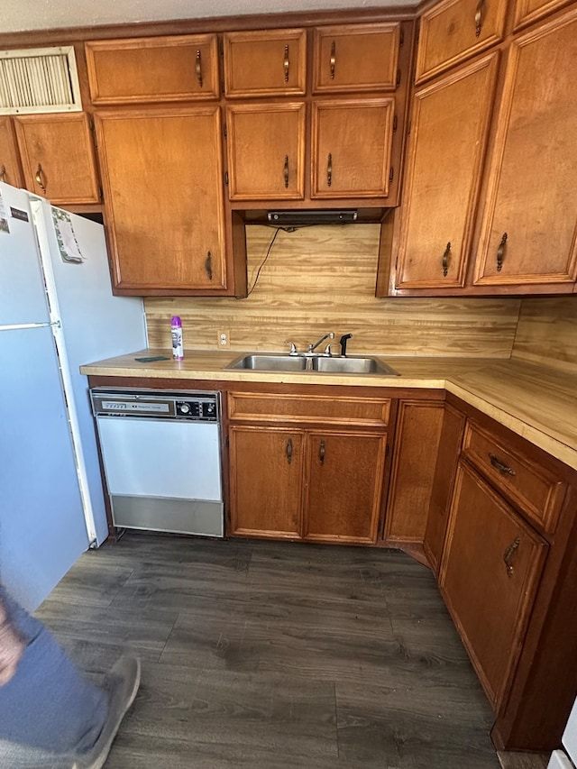 kitchen with dishwasher, light countertops, dark wood-type flooring, and a sink