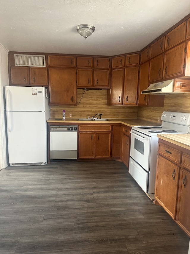 kitchen with brown cabinetry, white appliances, light countertops, and under cabinet range hood