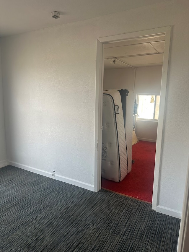 interior space with dark colored carpet and baseboards