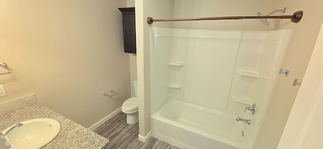 bathroom with baseboards, toilet, shower / bathing tub combination, wood finished floors, and vanity