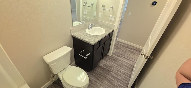 bathroom featuring baseboards, toilet, wood finished floors, and vanity