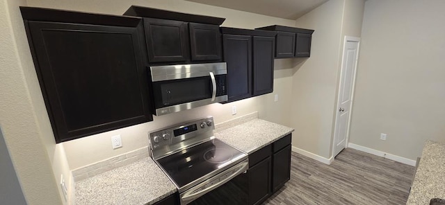 kitchen featuring light wood-style flooring, appliances with stainless steel finishes, dark cabinets, and light countertops