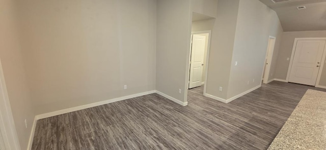 unfurnished room featuring dark wood-type flooring, baseboards, and vaulted ceiling