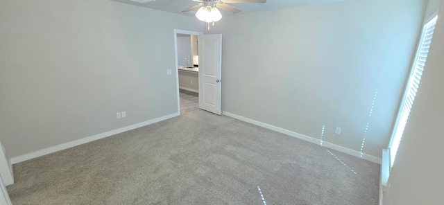 unfurnished bedroom with light colored carpet, a ceiling fan, and baseboards