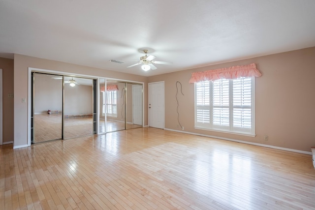 unfurnished bedroom with multiple closets, ceiling fan, and light wood-type flooring