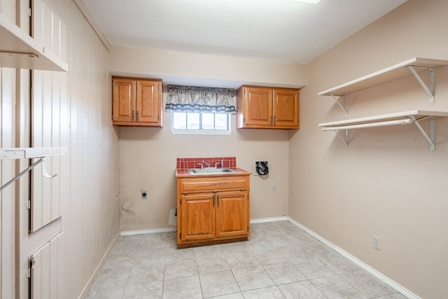 clothes washing area with sink, cabinets, a textured ceiling, light tile patterned floors, and electric dryer hookup