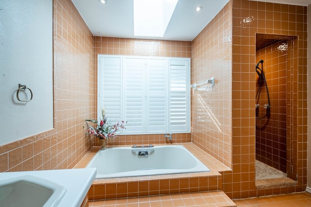 bathroom with plus walk in shower, tile walls, and a skylight