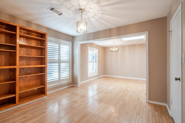 spare room featuring light hardwood / wood-style flooring and a notable chandelier