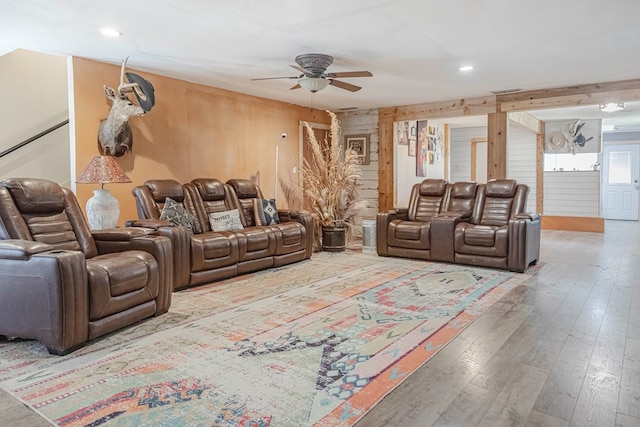 living room with ceiling fan, wood-type flooring, and wood walls