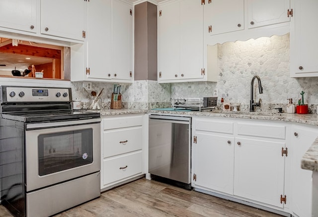 kitchen featuring white cabinets, backsplash, stainless steel appliances, and light hardwood / wood-style flooring