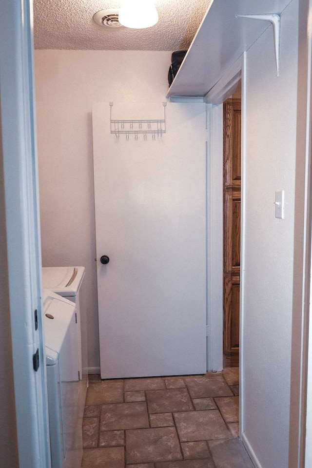 laundry area with washer and clothes dryer and a textured ceiling