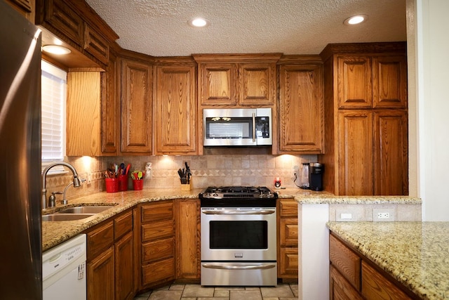 kitchen with light stone counters, sink, backsplash, and stainless steel appliances