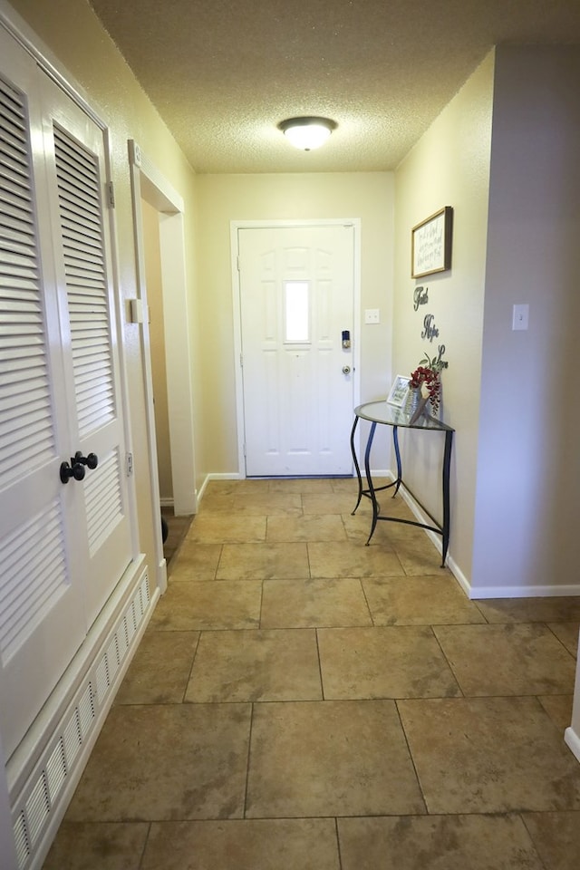 doorway to outside featuring light tile patterned floors and a textured ceiling