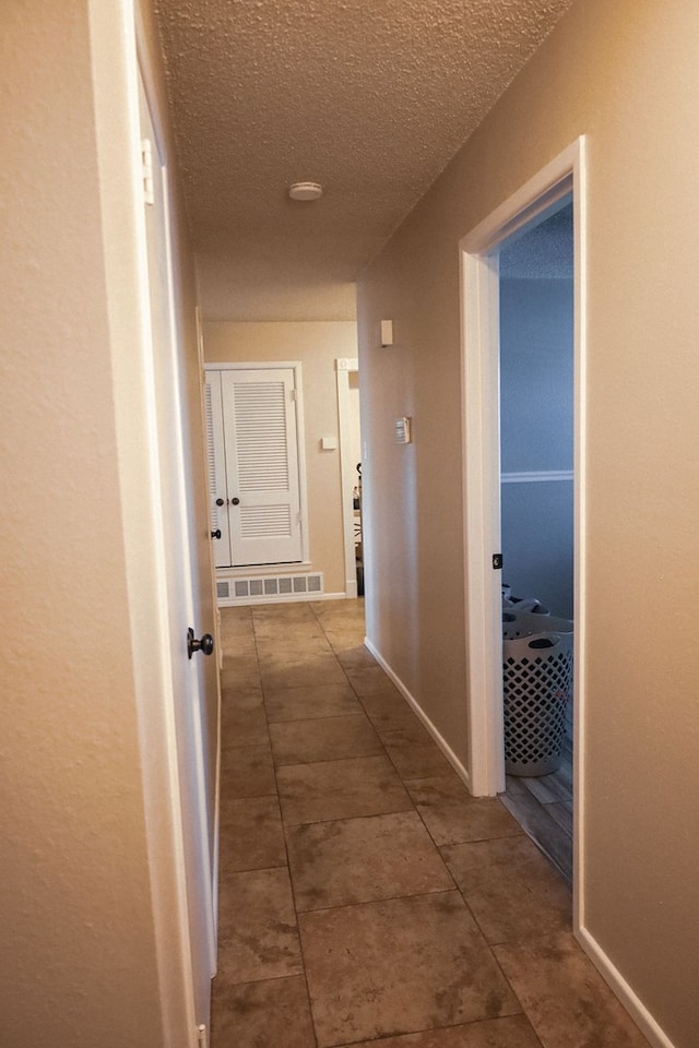 hallway with tile patterned flooring and a textured ceiling